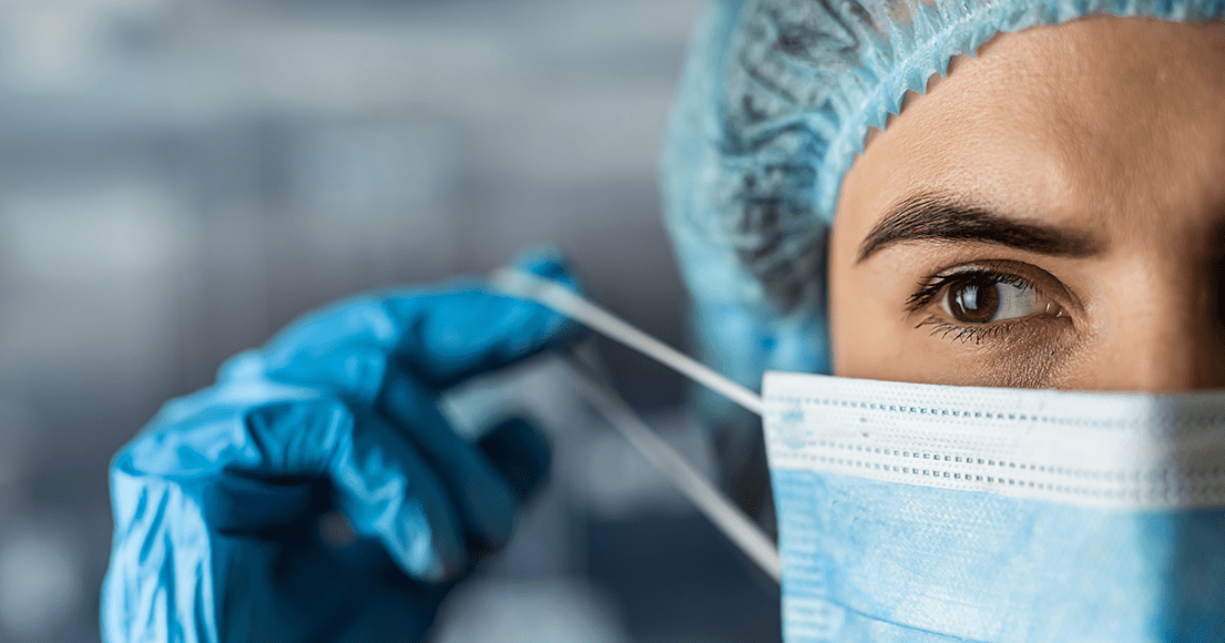 Sundhedsfaglig personale med hårnet og plastikhandsker, som tager mundbind på